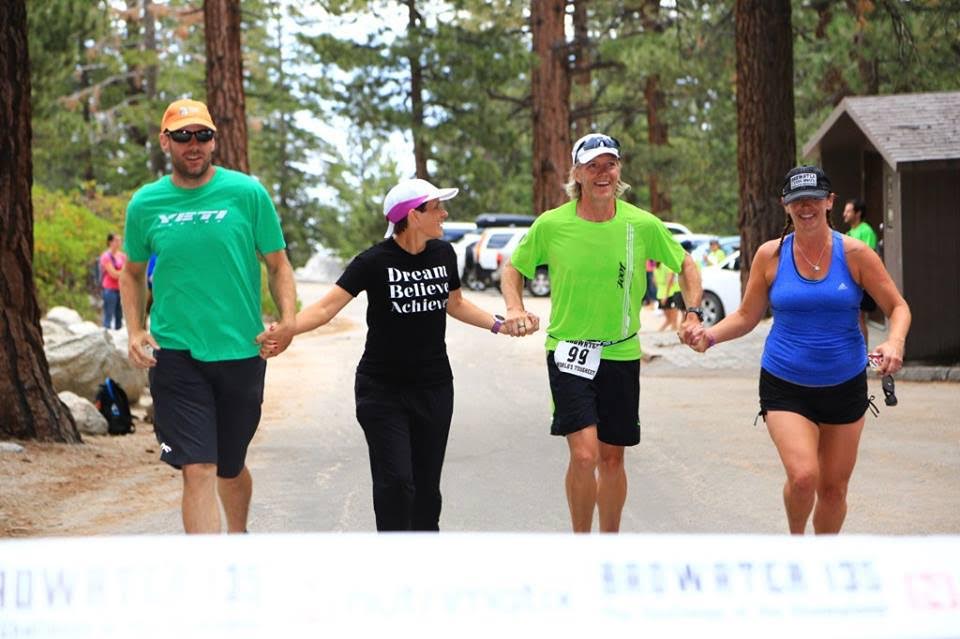 Two crew members flank Melanie Owen and her runner, Greg Pressler, as they approach the finish line. (Photo provided)