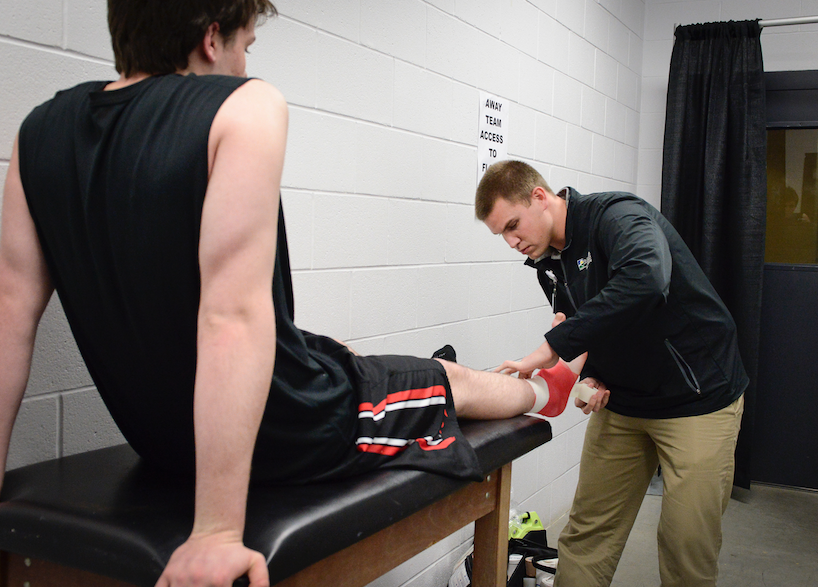 Trainer Tyler Watson tapes Holy Cross High School student-athlete Tyler Bezoid (Photo provided)